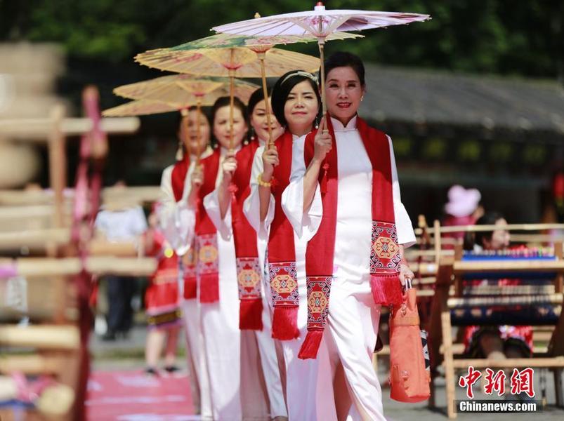 6月7日，第十三個中國“文化和自然遺產(chǎn)日”即將來臨之際，近百名土家織錦工人走進世界自然遺產(chǎn)地湖南張家界武陵源，在山水峰林間向中外游客展示國家級非物質文化遺產(chǎn)土家織錦技藝。當?shù)仄炫蹛酆谜哌€現(xiàn)場走秀，展示土家織錦提包、圍巾等旅游產(chǎn)品。中新社發(fā) 吳勇兵 攝